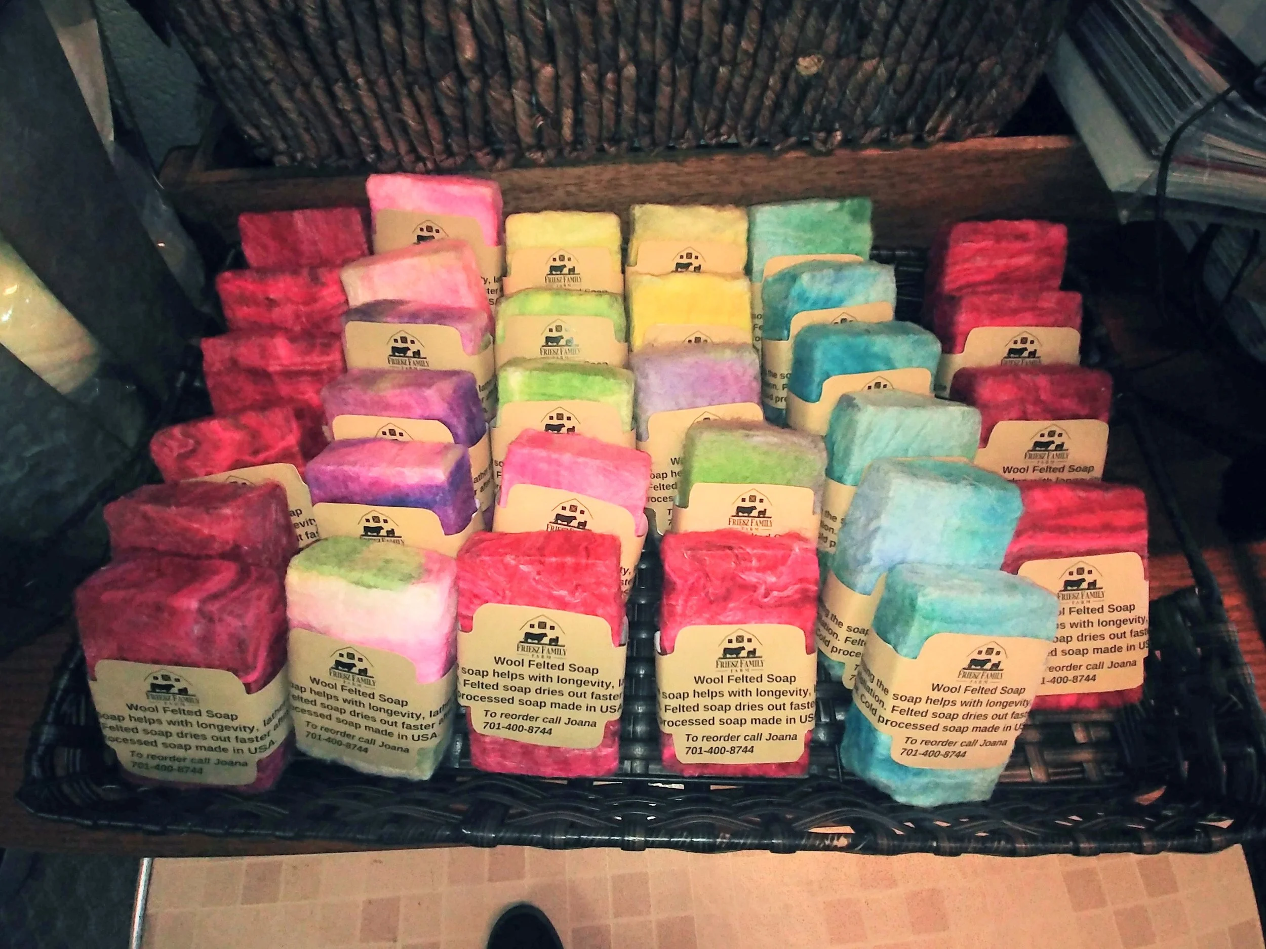 Rows of colourful wrapped felted soaps in a crate