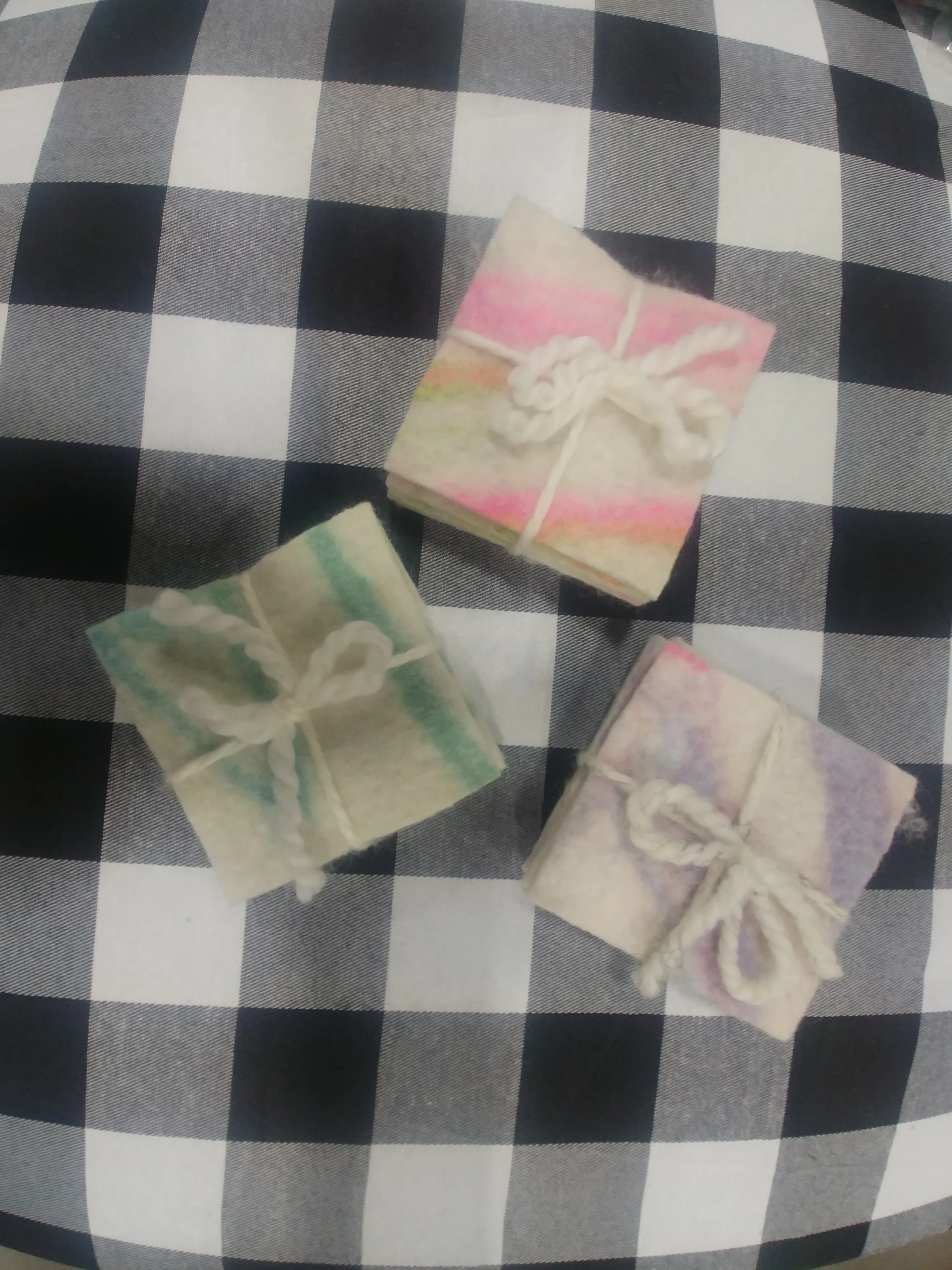 Three wrapped felted soap bars on a checked cloth
